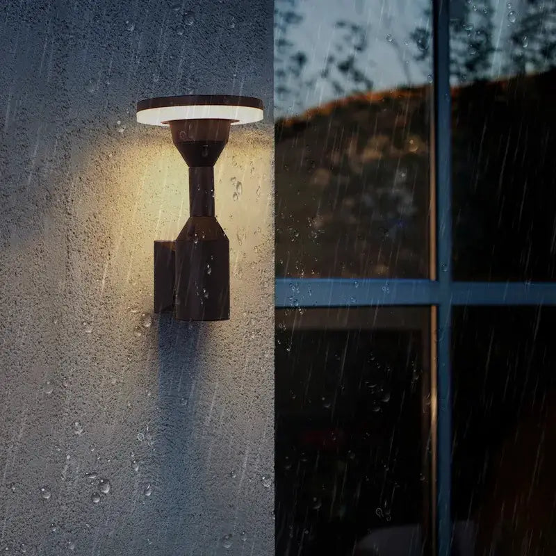 Modern black DecorBites™ LED outdoor wall lamp with circular illuminated top emitting warm light for garden or balcony