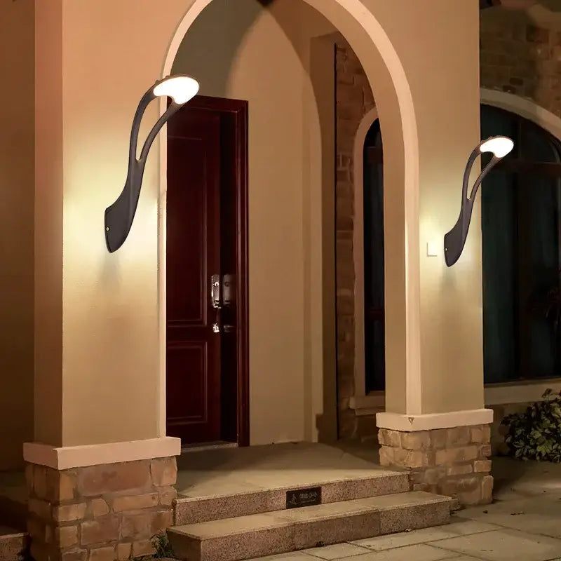 Black wrought iron decorbites™ outdoor wall lamp with curved leaf-like arms and warm white led lights for garden use