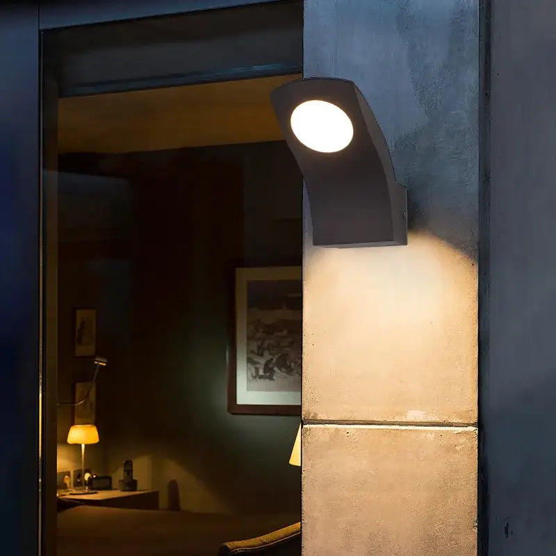 Modern black curved DecorBites™ LED outdoor wall lamp emitting warm circular light for garden balcony and courtyard use