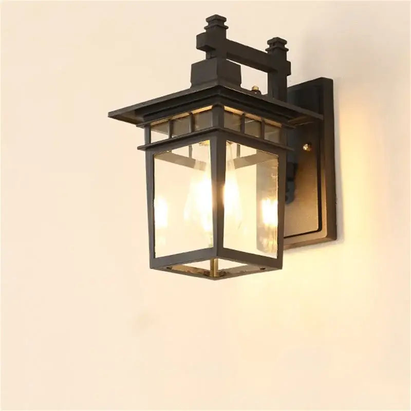 Black wrought iron decorbites led outdoor wall lamp with clear glass panels and warm glowing led light inside