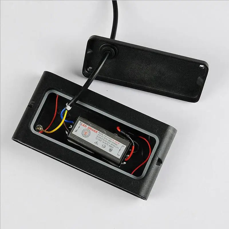 Black rectangular led driver with wiring and label inside open black plastic casing of decorbites led outdoor wall light