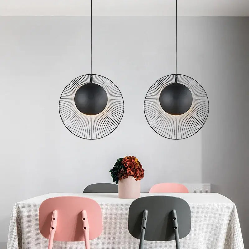 Two black wireframe oyster pendant lamps hang above a dining table as adjustable loft bedroom lighting