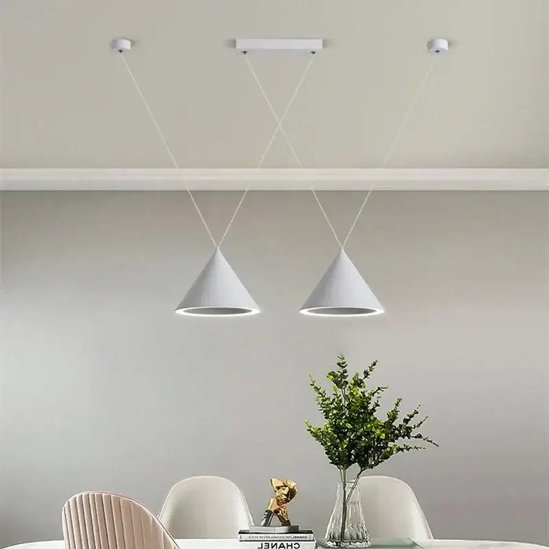 Two sleek white conical decorbites led pendant lights hang by cords in a minimalist dining space pendant light design