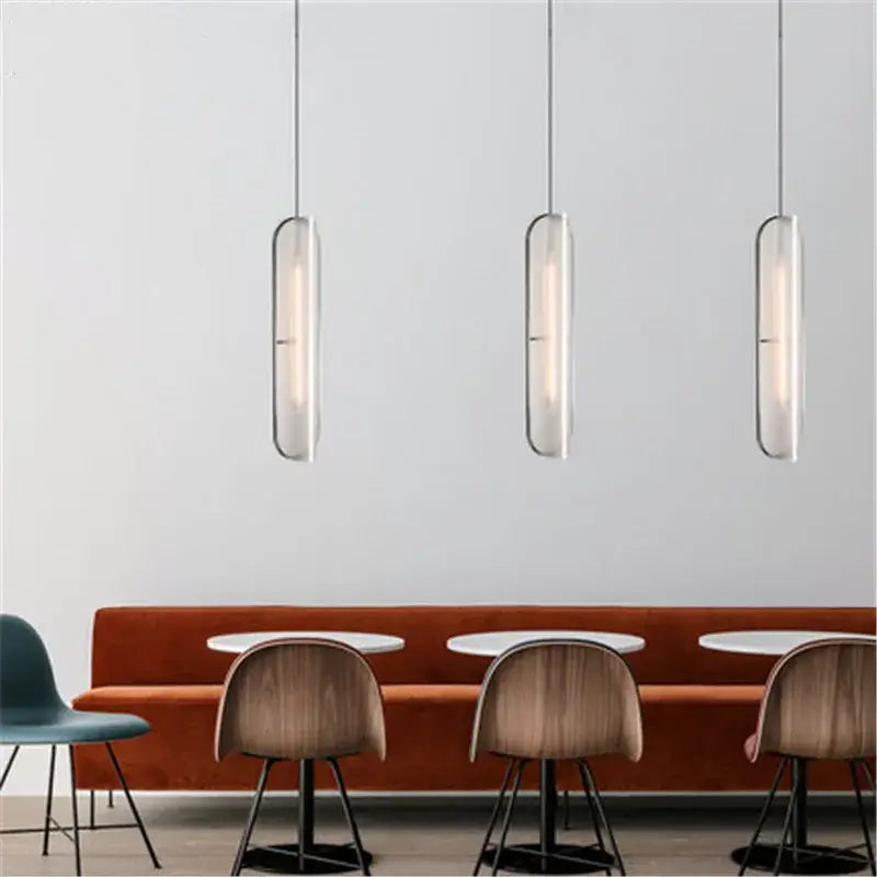 Three sleek frosted glass decorbites led pendant lamps with metallic frames hang in a modern dining space