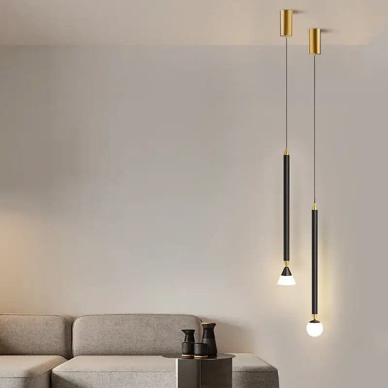 Two minimalist decorbites led pendant lights with gold cylindrical fixtures black rods and frosted globe bulbs for modern spaces