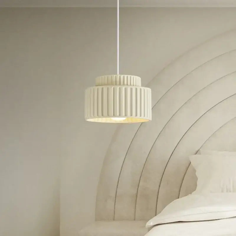 Cream-colored ribbed DecorBites led pendant lamp with modern resin design hanging above the bed