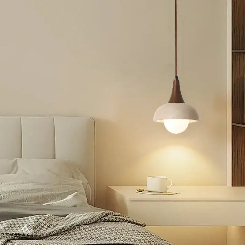 Modern decorbites led pendant lamp with matte white ceramic shade and dark bronze stem above bedside table