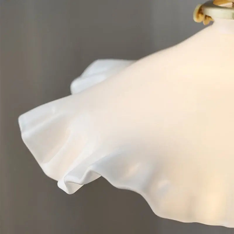 A decorbites led pendant lamp with white satin ruffle shade and adjustable brass knob switch catching the light