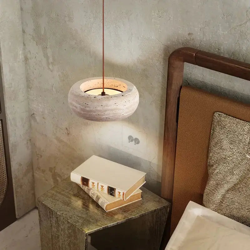 Minimalist DecorBites led pendant lamp with warm glowing yellow travertine interior and textured off-white concrete exterior