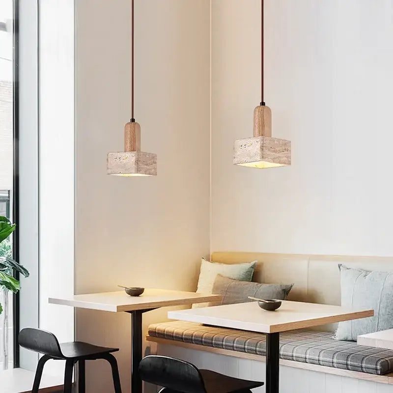 Two decorbites™ led pendant lights with yellow travertine stone shades and wood accents hang above a dining nook