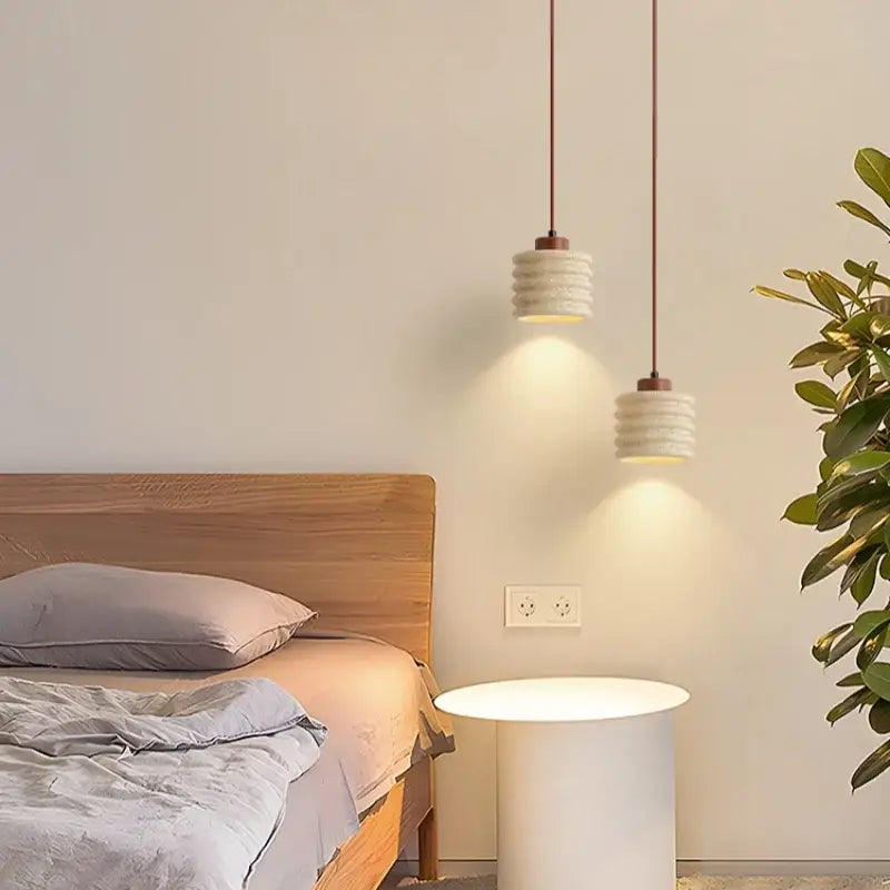 Two off-white decorbites led pendant lamps with stacked ring design hang above a white side table on copper cords