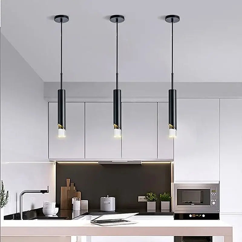 Three sleek black decorbites led pendant lamps with gold-accented acrylic bases hang above a modern kitchen counter