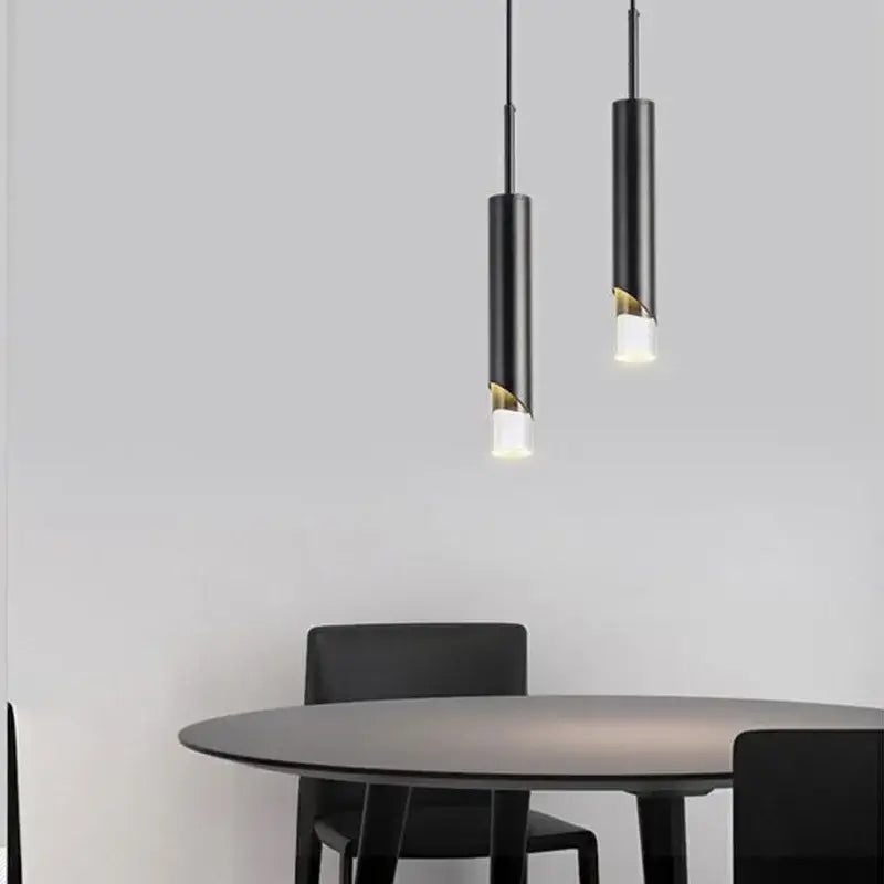 Two black DecorBites LED pendant lamps with gold-accented acrylic cutouts hang above a modern dining table