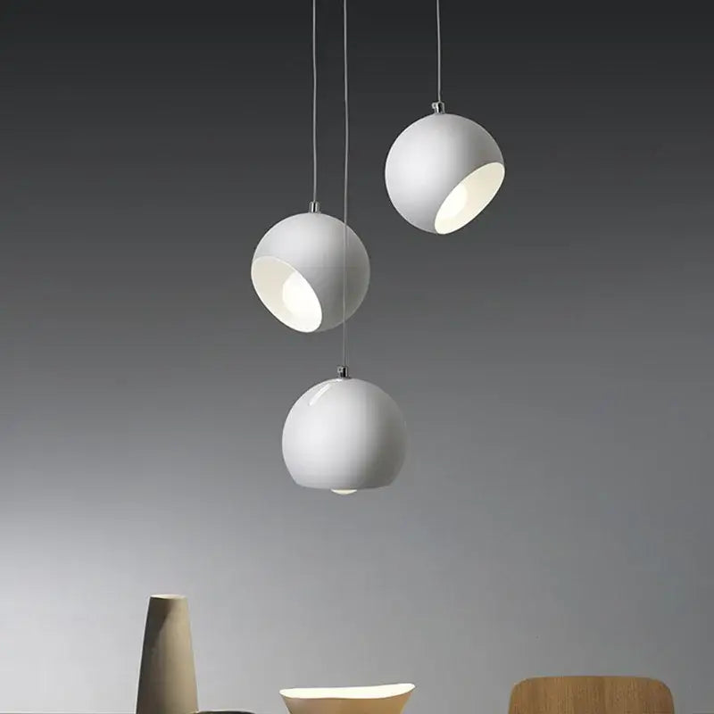 Three minimalist white spherical decorbites led pendant lights with matte finish hanging and emitting soft illumination