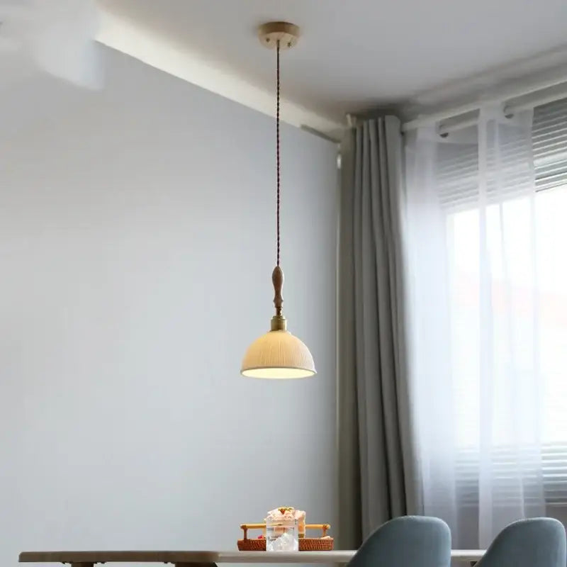 A warm-toned decorbites led pendant light with woven fabric shade and brass accents hangs from wooden ceiling mount