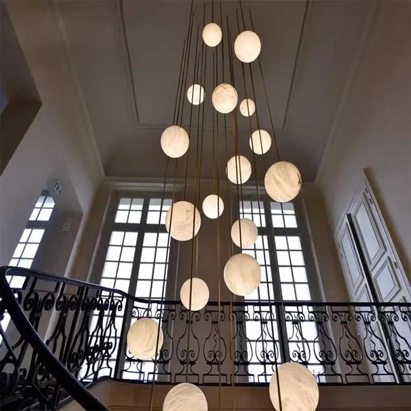A decorbites led pendant featuring off-white marble-like spherical orbs on thin metallic rods for indoor lighting