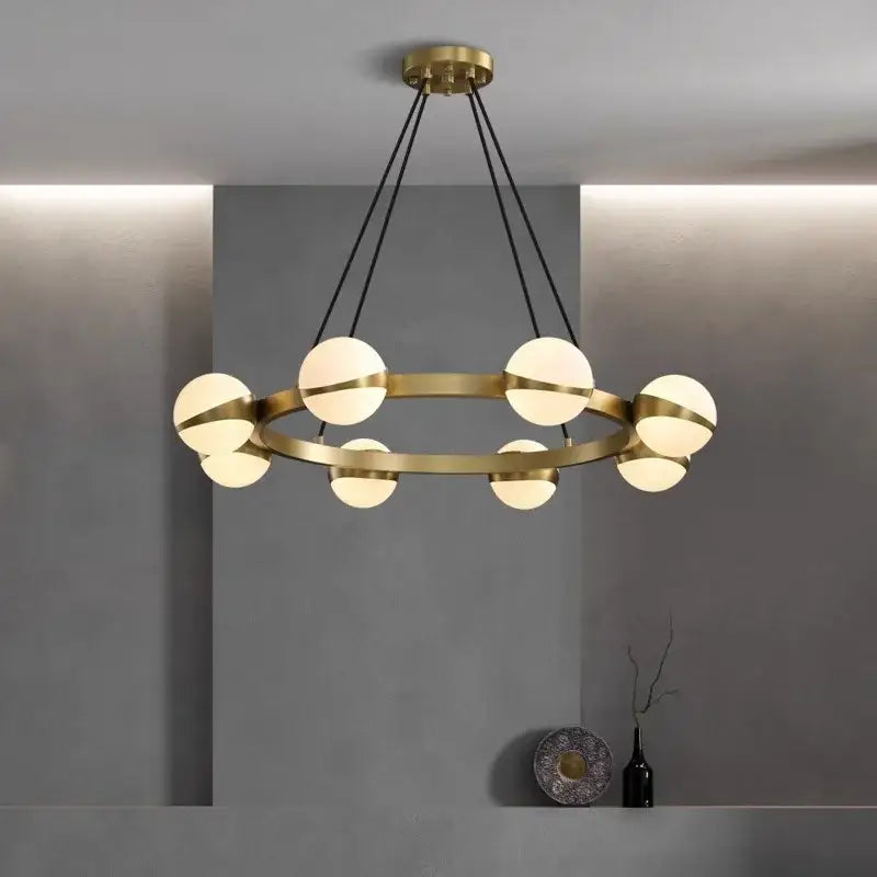 Modern brass DecorBites led pendant chandelier with eight frosted glass globe lights and black cords for indoor lighting