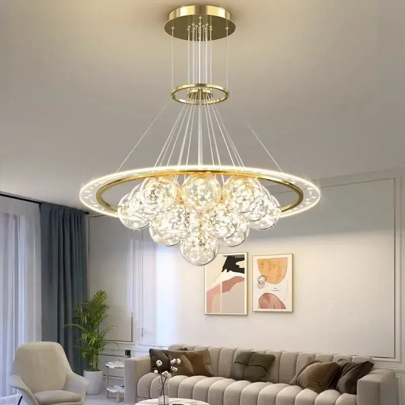 Gold-toned decorbites led pendant light chandelier with circular frame and clear faceted glass orbs for modern decor