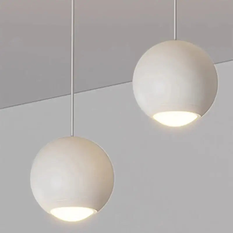 Two minimalist white spherical decorbites led pendant lights with sleek metal cords for modern indoor lighting