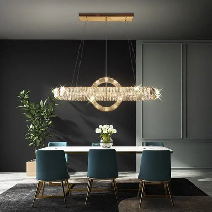 A modern gold-toned decorbites led pendant light chandelier with crystal rectangular body above a dining table