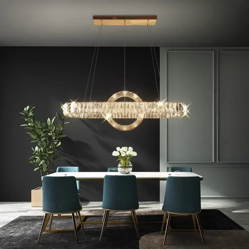 A modern gold-toned decorbites led pendant light chandelier with crystal rectangular body above a dining table