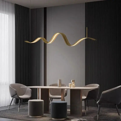 A sleek golden wave-shaped decorbites led pendant light hangs above a dining table for modern living and dining rooms