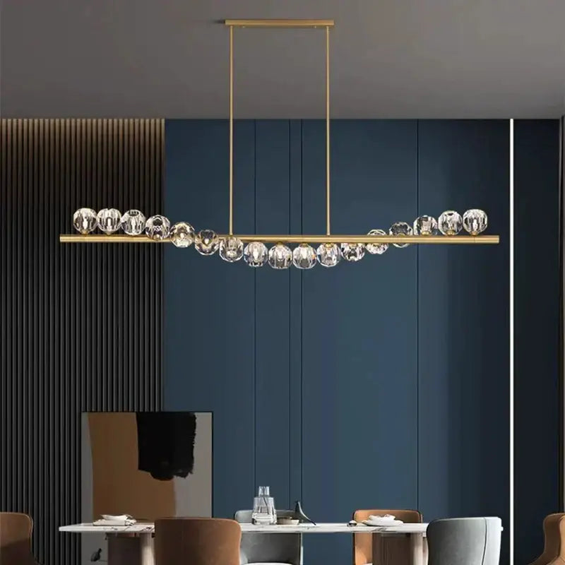 Gold-toned decorbites led pendant light chandelier with a sleek bar and faceted crystal spheres for modern living rooms