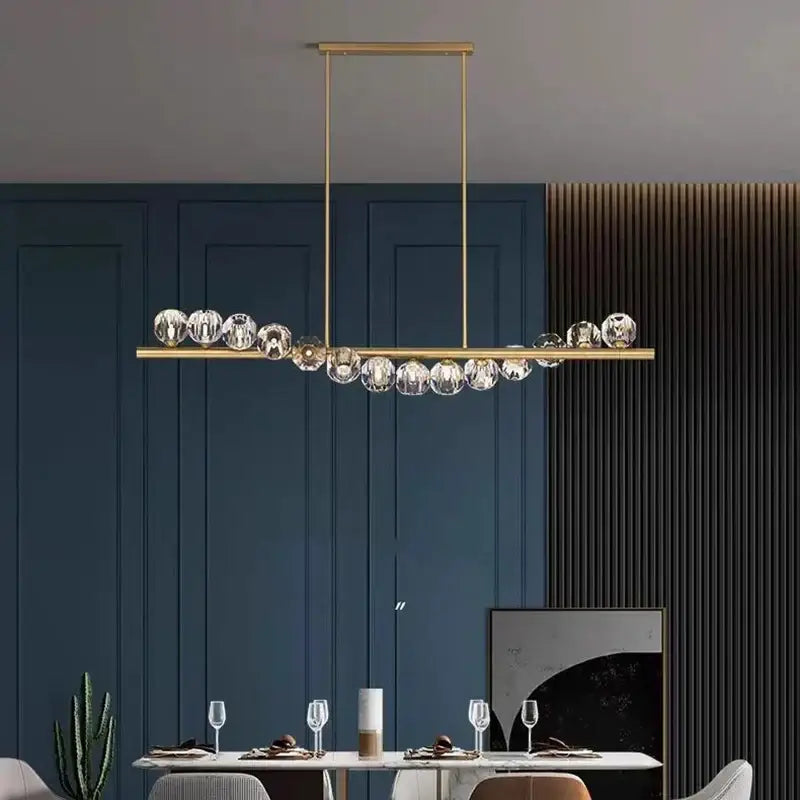 Gold-toned DecorBites LED pendant chandelier with sleek bar and faceted crystal spheres for modern living and dining rooms