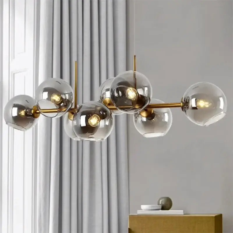 Modern gold-toned decorbites led pendant chandelier with clear glass spheres and exposed bulbs for living room lighting