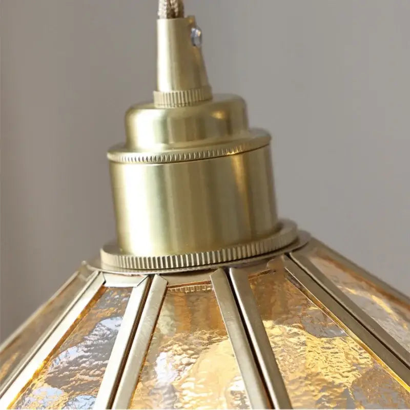 Brass-finished decorbites led pendant light with textured amber glass panels and metallic framing for modern living room