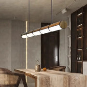 Modern cylindrical DecorBites LED pendant light with natural wood finish and metallic accents for living and dining rooms