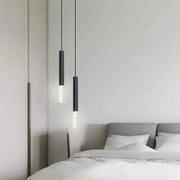 Two sleek black DecorBites LED pendant lights with frosted glass accents hang above a bed in a living room