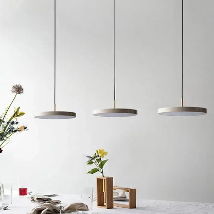 Three black matte iron decorbites led pendant lights with circular shades hang in a modern dining space