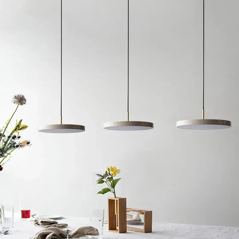 Three black matte iron decorbites led pendant lights with circular shades hang in a modern dining space