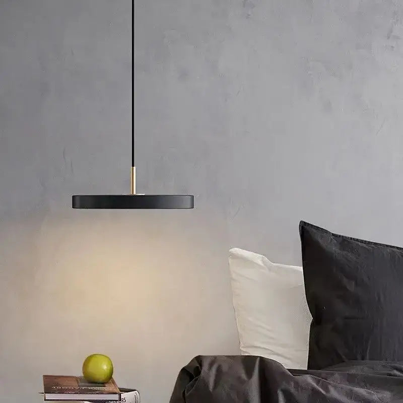 Black circular iron pendant light with slender gold-toned stem hanging above bed decorbites led pendant light