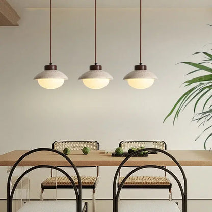 Three decorbites led pendant lights with textured concrete shades and warm glow hang above a dining table
