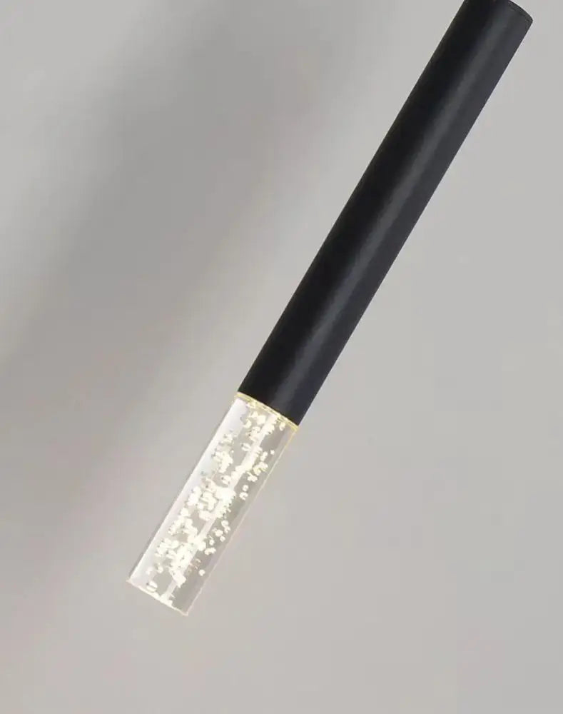 Black cylindrical decorbites led pendant light with clear illuminated glass base and floating white particles for indoor use