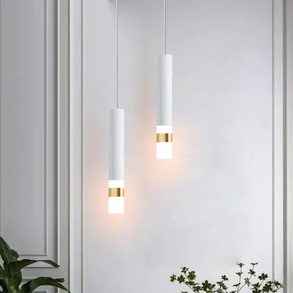 Two minimalist white matte cylindrical pendant lights with gold bands emitting warm glow decorbites led pendant light