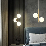 Modern gold-toned decorbites led pendant light with three glowing glass spheres hanging above a bed for home decor lighting