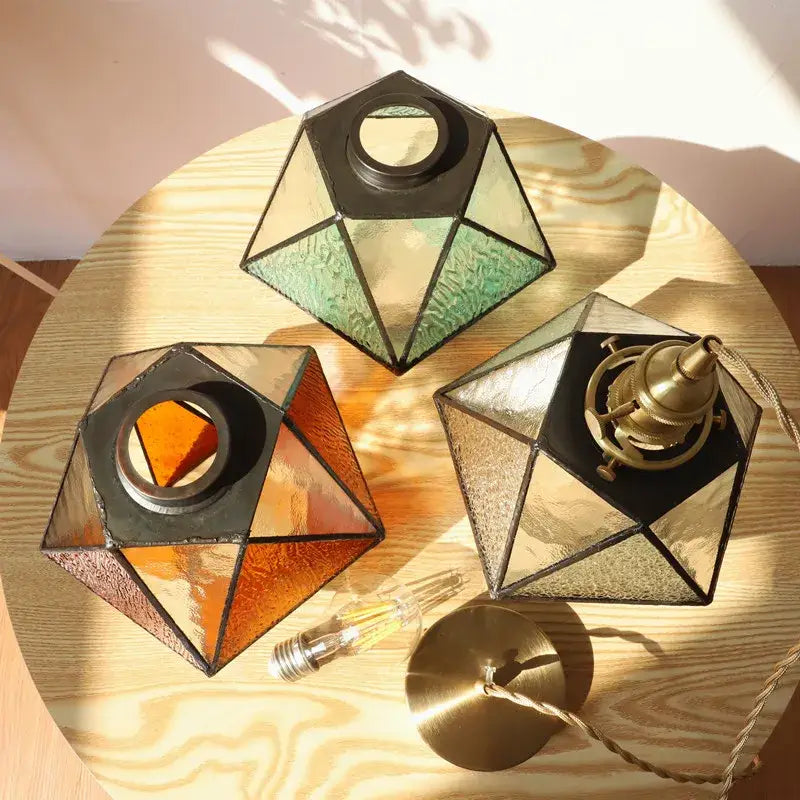 Three geometric stained glass pendant light shades with black metal frames in green orange and amber tones by decorbites led pendant