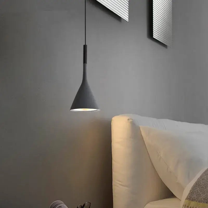 A sleek matte black DecorBites led pendant light with conical shade hangs above a sofa in nordic modern style