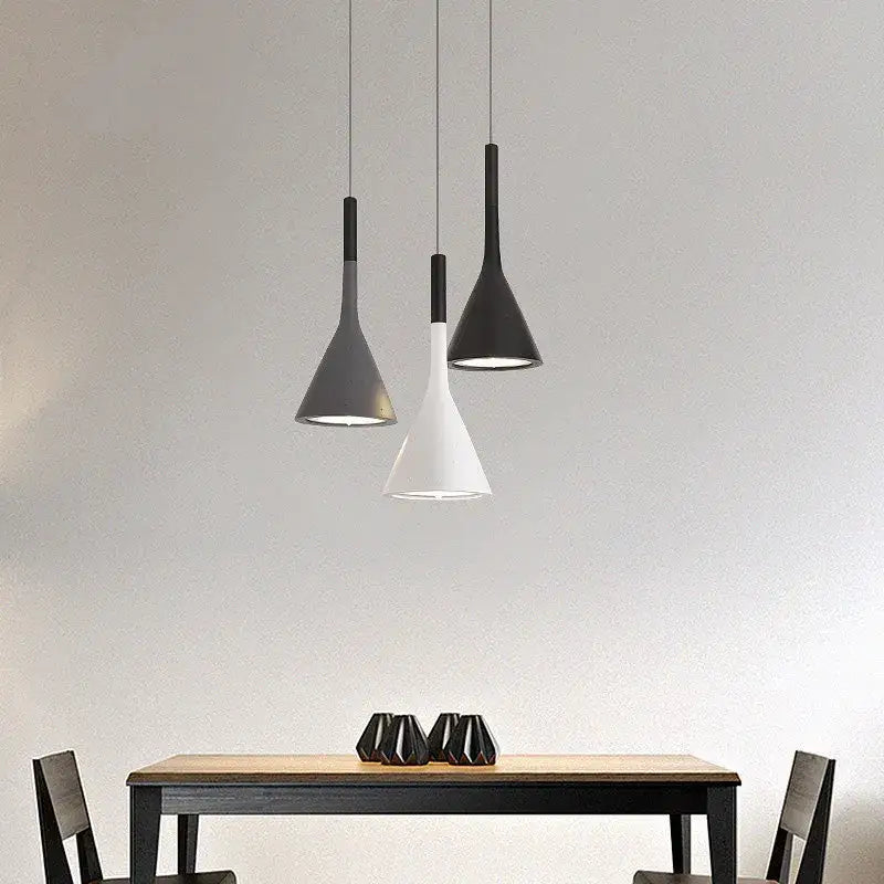 Three modern matte black and white decorbites led pendant lights with conical shades hang above a dining table