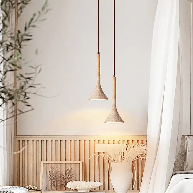 Two minimalist decorbites led pendant lights with yellow travertine ceramic shades and wooden stems hanging from dark cords