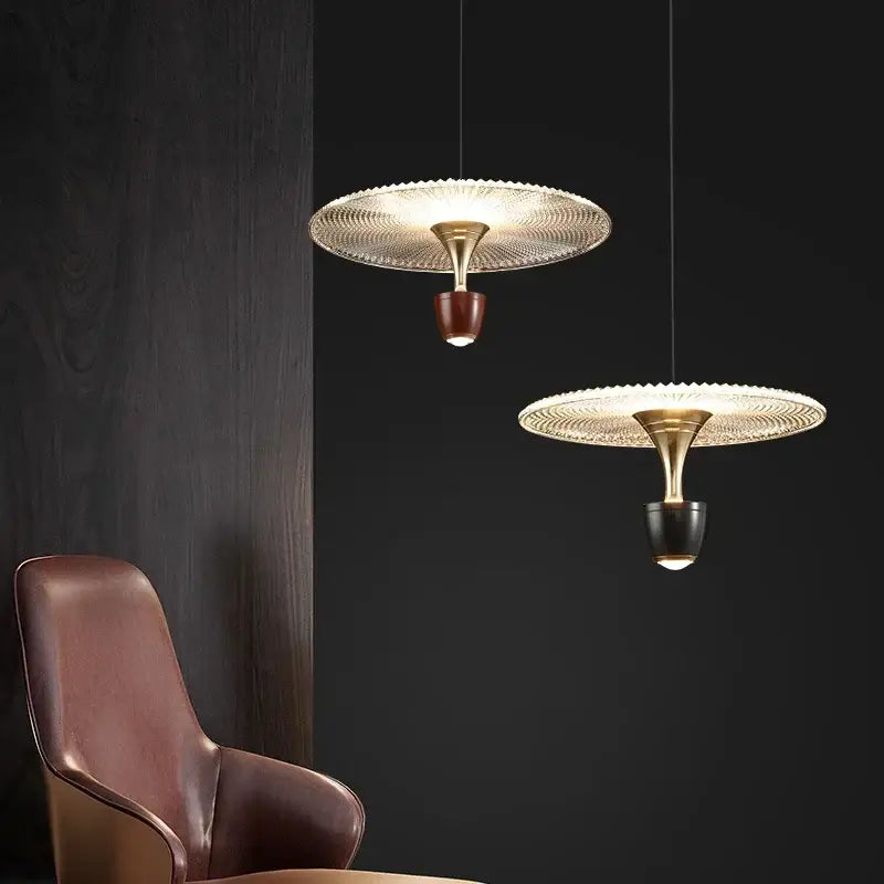 Two decorbites led pendant lamps with gold metal frames and textured glass shades in brown and black bases for adjustable lighting