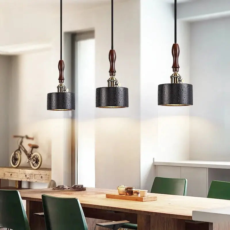 Three black travertine textured cylindrical pendant lights with dark wood fixtures decorbites led pendant light