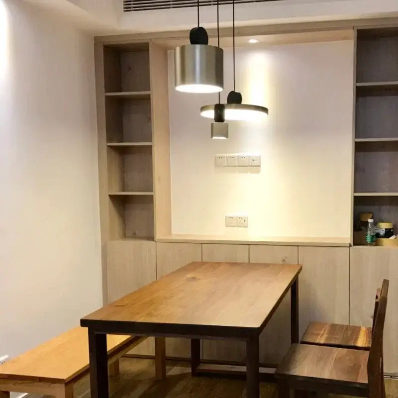 Modern minimalist decorbites led pendant lights with brushed metal cylindrical and disc shades above wooden table