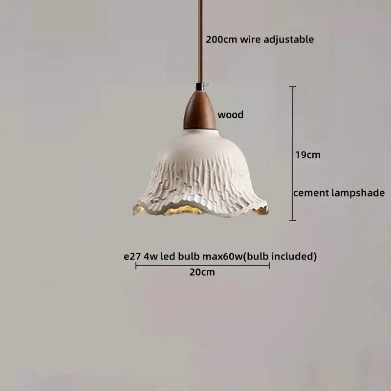A white, textured cement lampshade with a fluted design and gold-trimmed edge hangs from a wooden fixture.