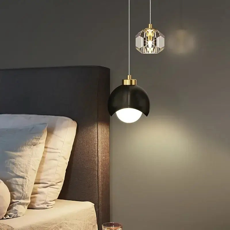Two decorbites led pendant lights with black matte dome and faceted crystal globe shades hang above a bed