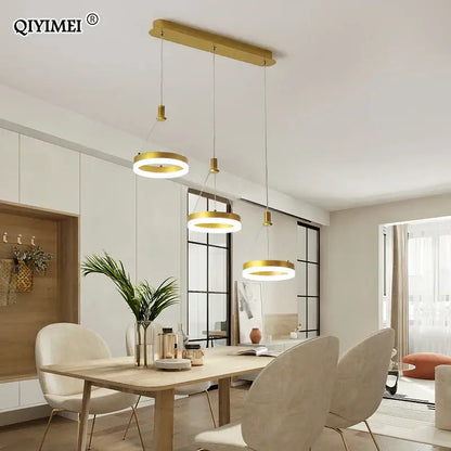 Gold-toned decorbites led pendant lights with circular shades hang from a black and white acrylic ceiling fixture