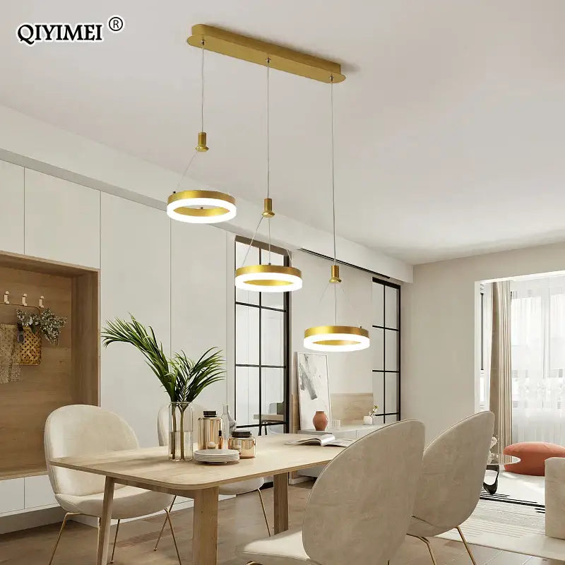 Gold-toned decorbites led pendant lights with circular shades hang from a black and white acrylic ceiling fixture